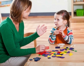 Preschool girl listening to teacher in classroom